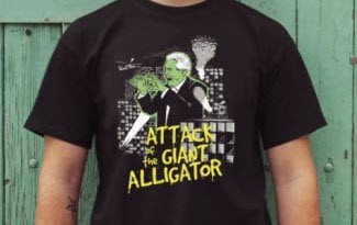 Černé tričko s potiskem Attack of the giant alligator, v hlavní roli pan prezident. Žlutý anglický text útok aligátora. Kresba Miloše Zemana na tričku